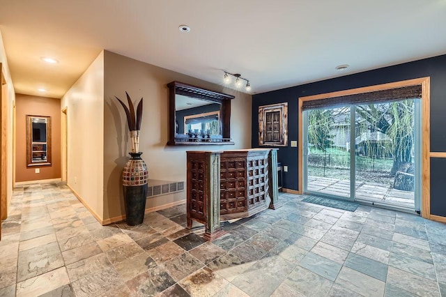 interior space with stone tile floors, baseboards, and rail lighting
