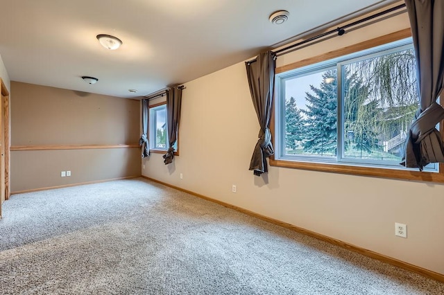 empty room featuring baseboards, a healthy amount of sunlight, and carpet