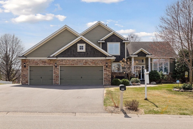 craftsman-style house featuring a front lawn, driveway, stone siding, and a garage
