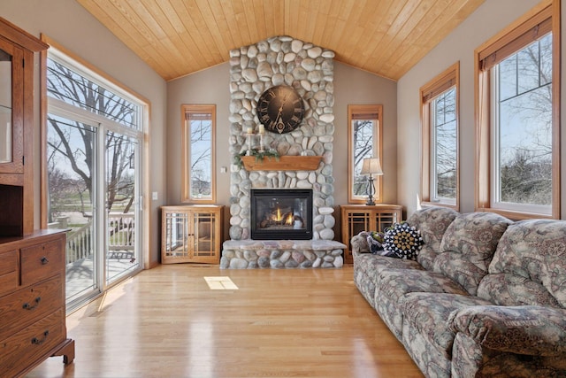 living area with plenty of natural light, wood finished floors, and a stone fireplace