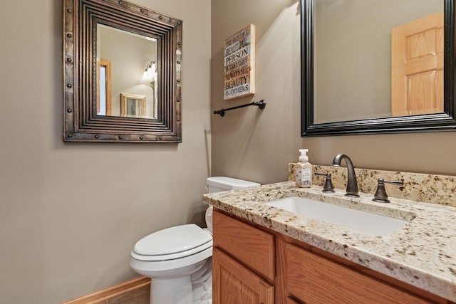 half bath featuring baseboards, toilet, and vanity