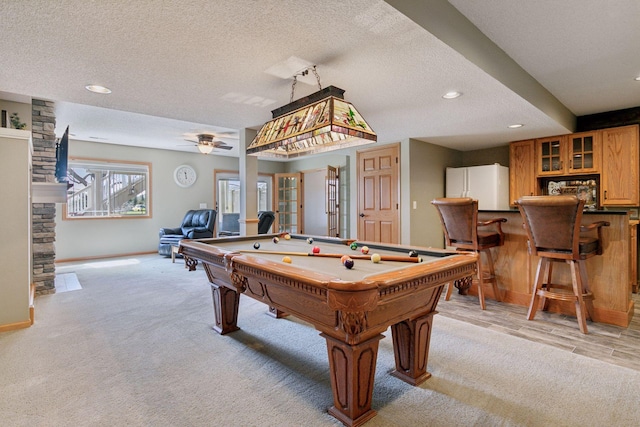 rec room with light colored carpet, billiards, a textured ceiling, and bar area