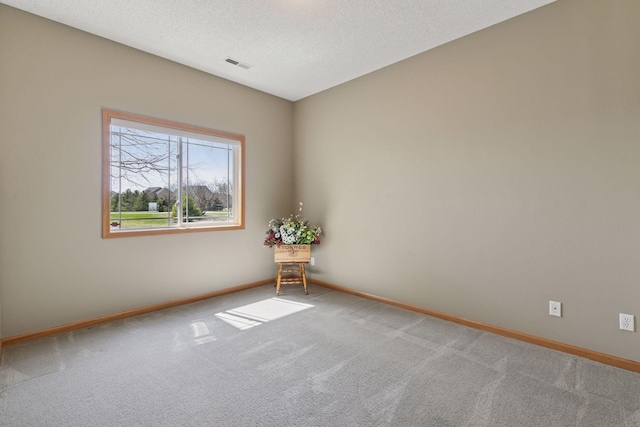 unfurnished room with a textured ceiling, carpet floors, visible vents, and baseboards