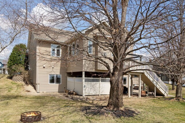 back of property featuring an outdoor fire pit, a yard, and stairs