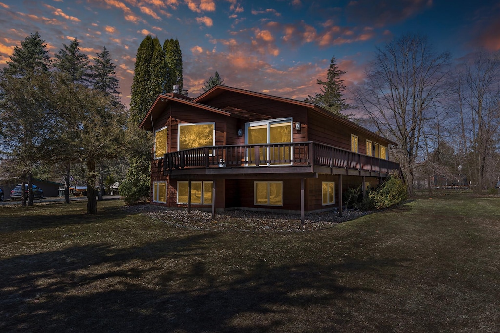 back of property at dusk with a yard and a wooden deck