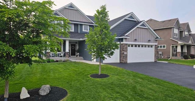 4737 130th Ln NE, Blaine, MN 55449 - craftsman-style house with board and batten siding, driveway, a front yard, stone siding, and a porch