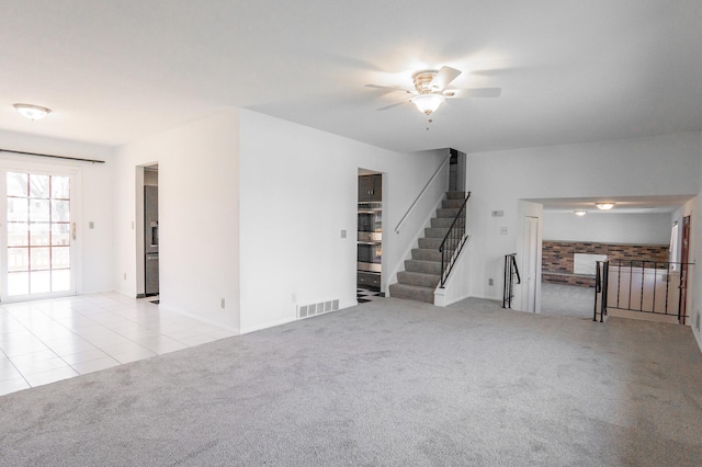 7740 Arlington Ave N, Brooklyn Park, MN 55443 - unfurnished living room featuring tile patterned floors, visible vents, carpet floors, stairs, and ceiling fan