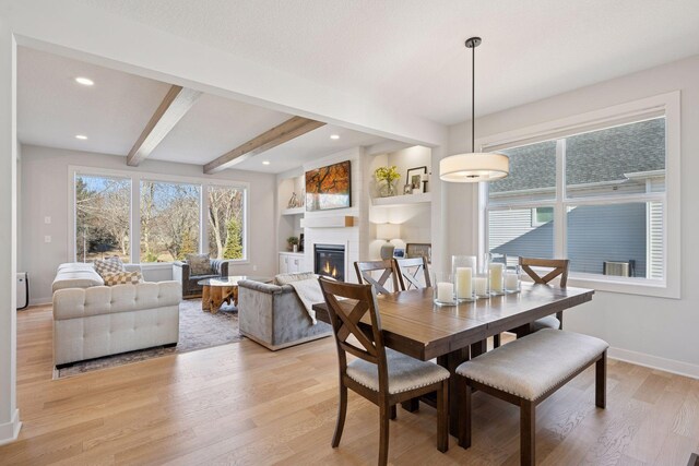 dining space featuring baseboards, light wood-type flooring, a fireplace, beam ceiling, and recessed lighting