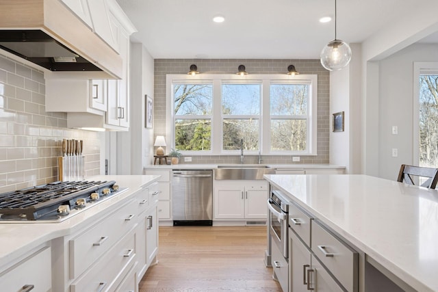 kitchen with light countertops, custom range hood, a sink, and stainless steel appliances