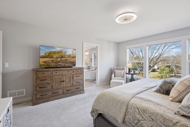 bedroom with baseboards, a textured ceiling, connected bathroom, visible vents, and light colored carpet