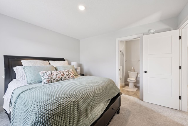 bedroom with connected bathroom and light colored carpet