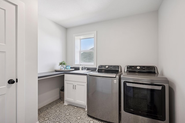 clothes washing area with baseboards, a sink, washing machine and clothes dryer, and cabinet space
