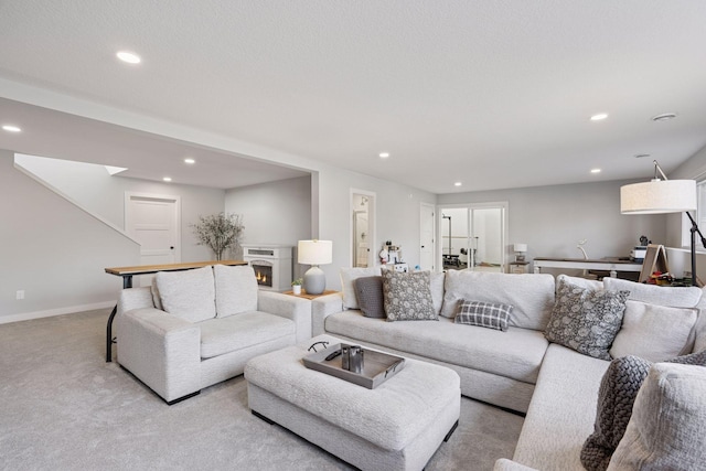 living room with a warm lit fireplace, baseboards, recessed lighting, and light colored carpet