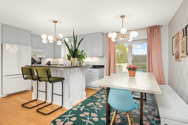 1602 River St, Monticello, MN 55362 - kitchen with white appliances, a chandelier, light wood-type flooring, and a kitchen bar
