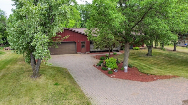 view of front of home with an attached garage, decorative driveway, and a front lawn