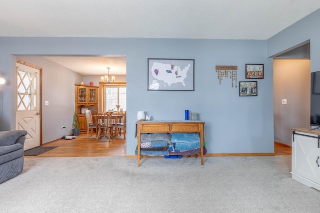 living area featuring carpet flooring, a chandelier, and baseboards