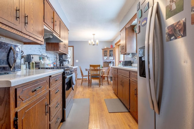 kitchen with stainless steel appliances, light wood-style flooring, a chandelier, and light countertops