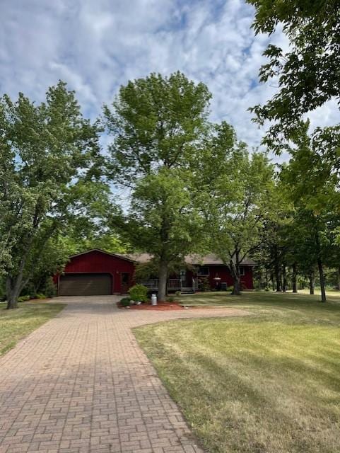 view of front of property featuring an attached garage, a front yard, and decorative driveway