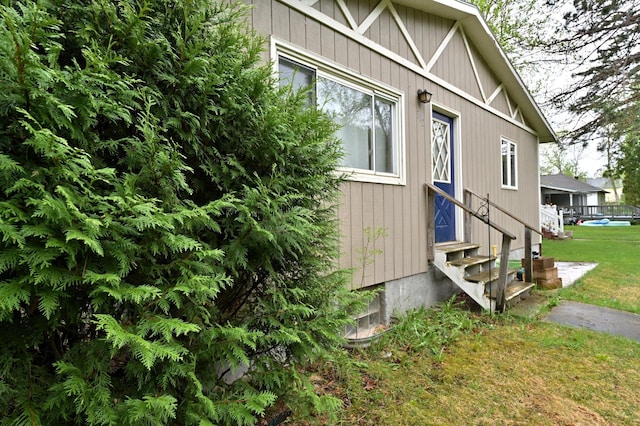 view of side of home with entry steps and a lawn
