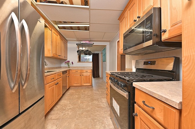 kitchen featuring appliances with stainless steel finishes, light countertops, a paneled ceiling, and a sink