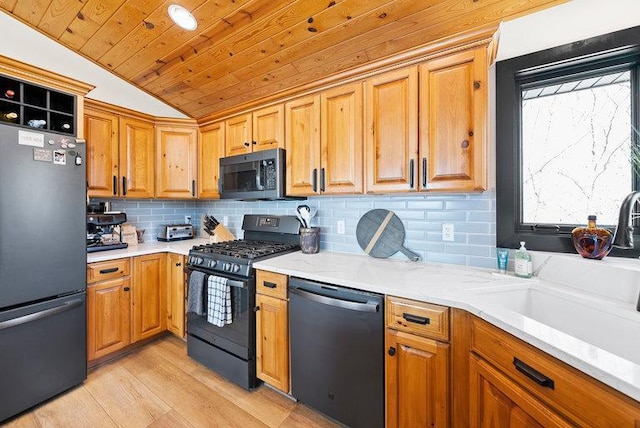 kitchen featuring a sink, freestanding refrigerator, stainless steel dishwasher, black gas range, and lofted ceiling