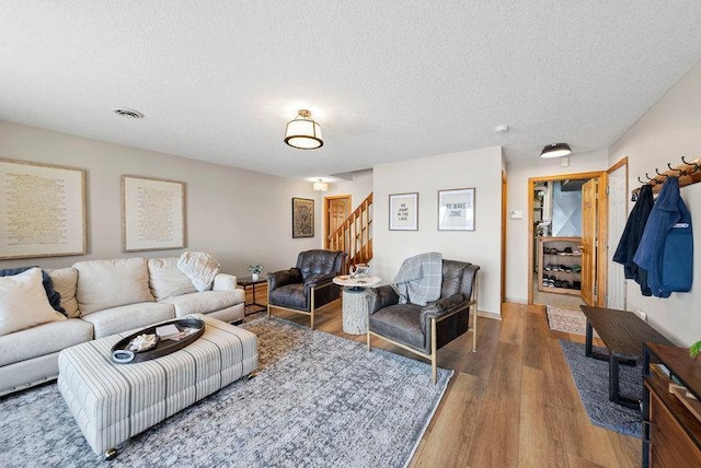 living room featuring a textured ceiling, wood finished floors, and stairs