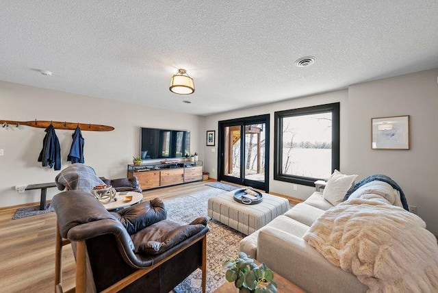 living area with baseboards, visible vents, a textured ceiling, and wood finished floors