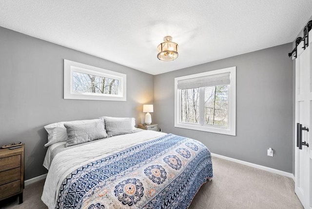 bedroom featuring a textured ceiling, carpet flooring, a barn door, and baseboards