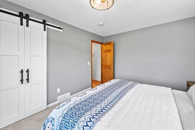 bedroom featuring visible vents, a barn door, baseboards, and carpet floors