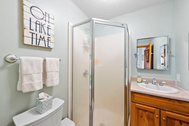 full bath featuring vanity, toilet, a stall shower, and a textured ceiling