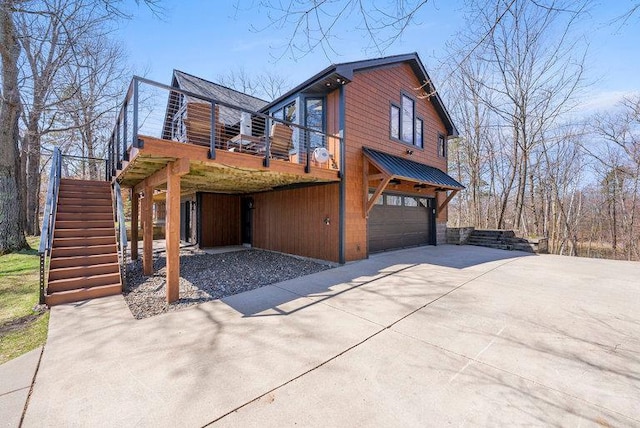 view of property exterior with an attached garage, concrete driveway, stairs, and a balcony