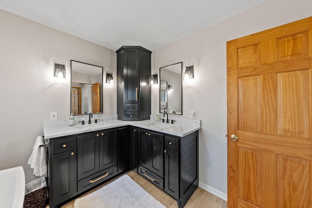 bathroom with double vanity, wood finished floors, and baseboards