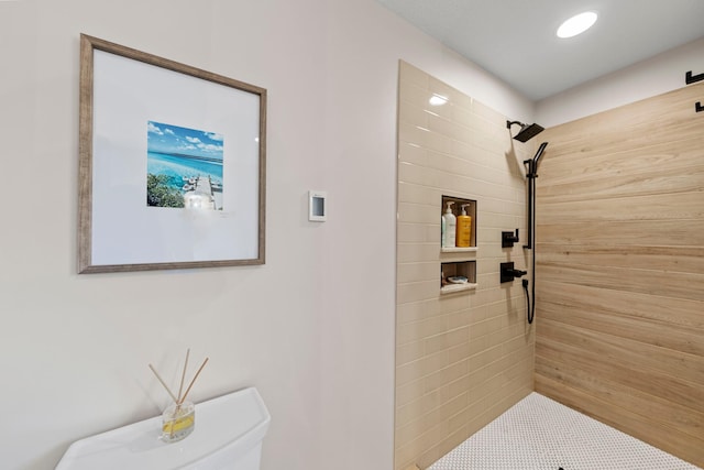 bathroom with a tile shower and toilet