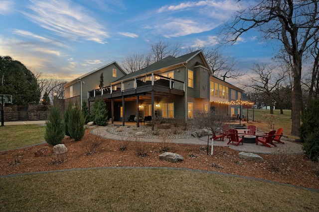 2834 12th Ave NW, Austin, MN 55912 - back of property at dusk featuring a fire pit, a patio, a lawn, and a wooden deck