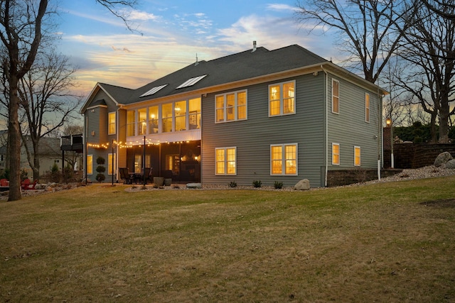 2834 12th Ave NW, Austin, MN 55912 - back of property at dusk featuring a yard, a patio, and a sunroom