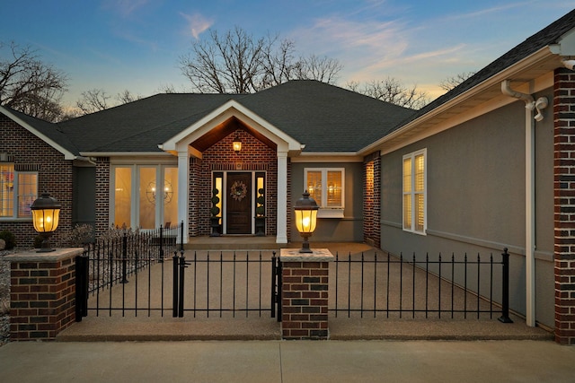 2834 12th Ave NW, Austin, MN 55912 - view of front of property with a fenced front yard, a gate, brick siding, stucco siding, and roof with shingles