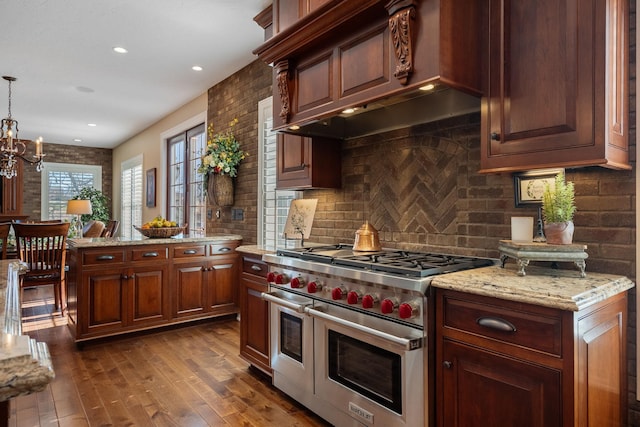 2834 12th Ave NW, Austin, MN 55912 - kitchen with double oven range, dark wood-style floors, a chandelier, decorative backsplash, and light stone counters