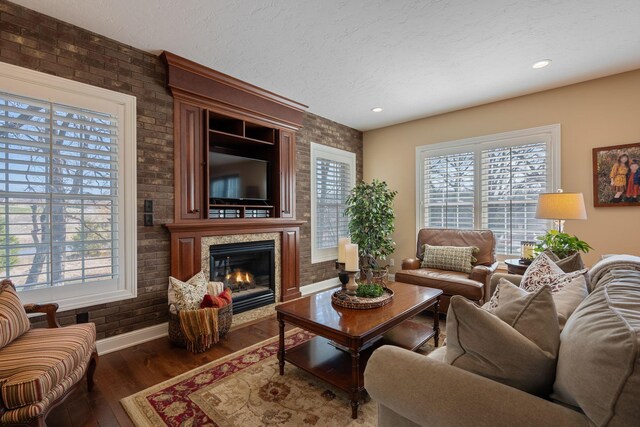 2834 12th Ave NW, Austin, MN 55912 - living area with baseboards, plenty of natural light, dark wood-style floors, a glass covered fireplace, and brick wall