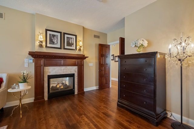 2834 12th Ave NW, Austin, MN 55912 - living area featuring dark wood-type flooring, a chandelier, a tiled fireplace, baseboards, and a textured ceiling