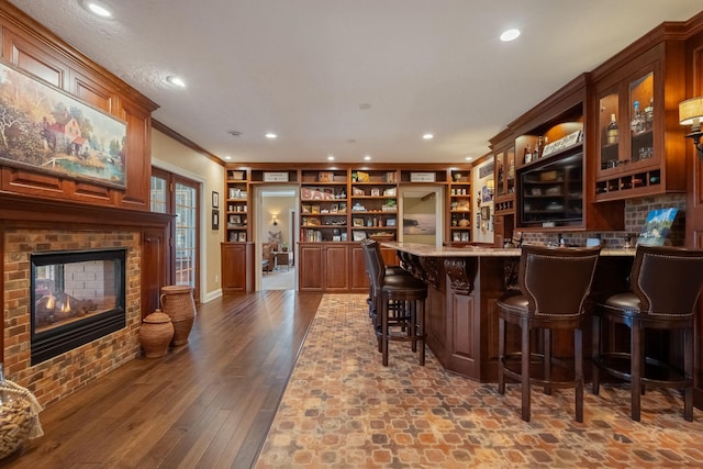 2834 12th Ave NW, Austin, MN 55912 - bar featuring crown molding, a multi sided fireplace, recessed lighting, dark wood-style floors, and built in features