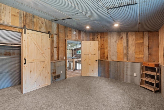 16688 248th St, Long Prairie, MN 56347 - carpeted spare room featuring wood walls, visible vents, and a barn door