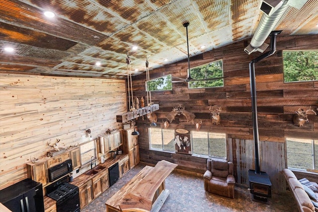 16688 248th St, Long Prairie, MN 56347 - unfurnished living room featuring a wood stove, wooden walls, a sink, and wooden ceiling