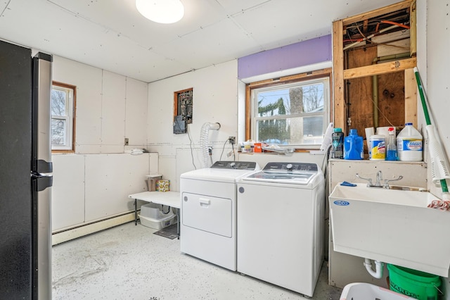 laundry area featuring washing machine and dryer, laundry area, a sink, and baseboard heating