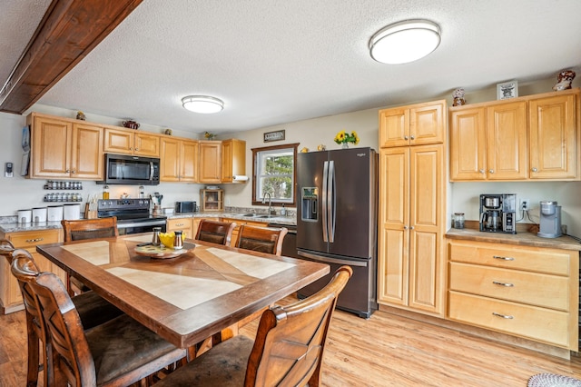 kitchen featuring refrigerator with ice dispenser, stainless steel electric range oven, light brown cabinets, light wood finished floors, and a textured ceiling