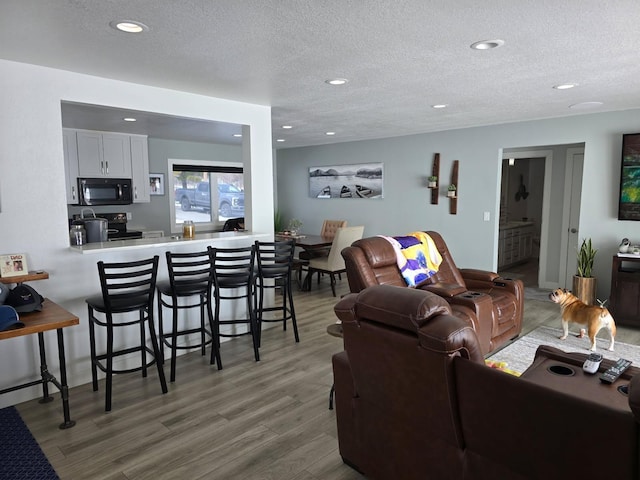 living area featuring recessed lighting, a textured ceiling, and wood finished floors