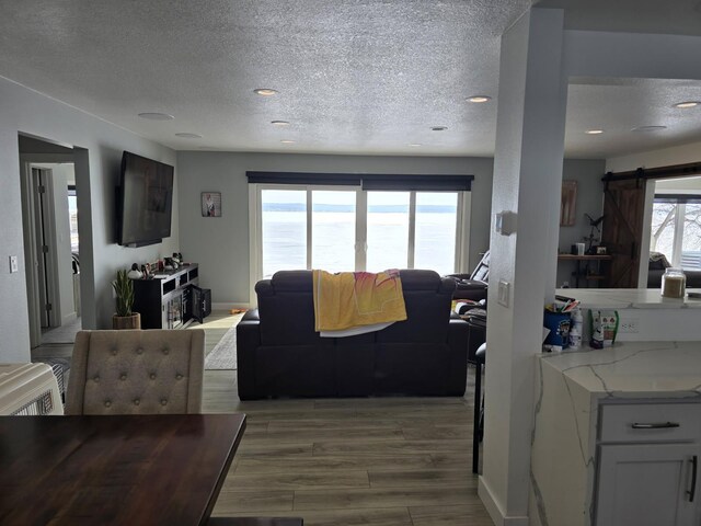 living area with recessed lighting, a textured ceiling, and light wood finished floors