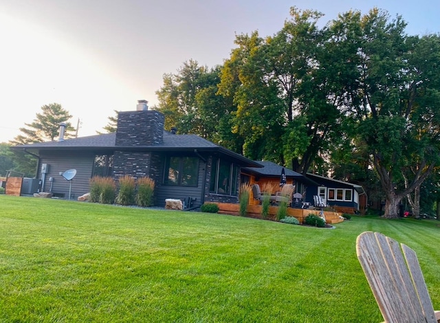 rear view of house featuring a yard and a chimney