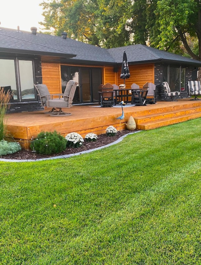 back of house featuring roof with shingles, a yard, and a deck