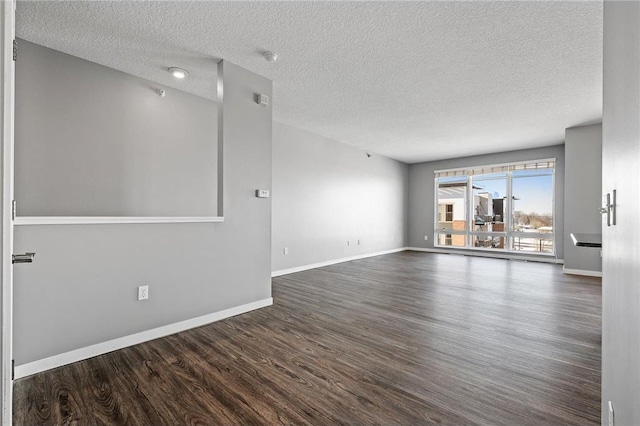 spare room featuring baseboards, wood finished floors, and a textured ceiling