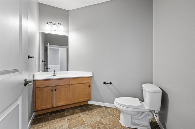 bathroom featuring stone finish floor, vanity, baseboards, and toilet